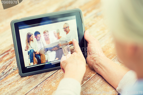 Image of senior woman with family photo on tablet pc screen