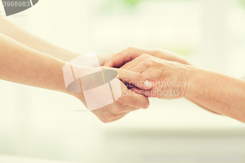 Image of close up of senior and young woman holding hands