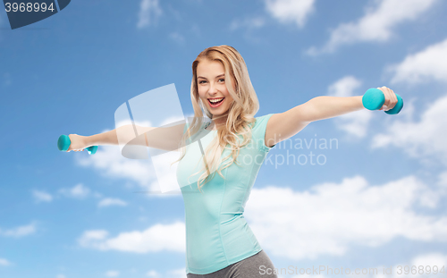 Image of smiling beautiful young sporty woman with dumbbell