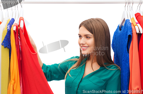 Image of happy woman choosing clothes at home wardrobe