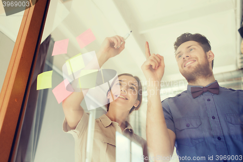 Image of happy creative team writing on blank office glass