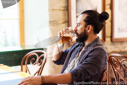 Image of happy man drinking beer at bar or pub