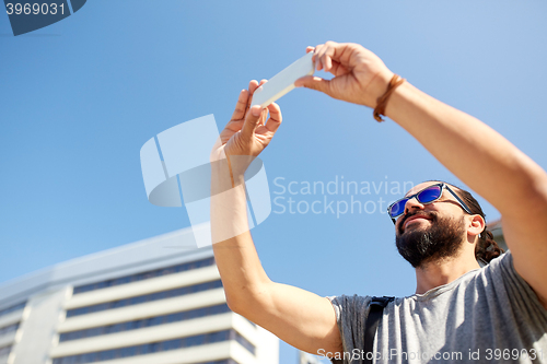 Image of man taking video or selfie by smartphone in city