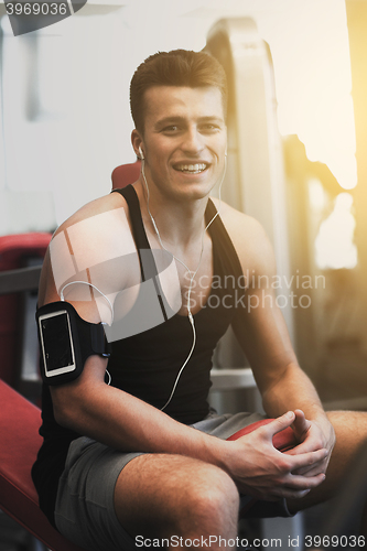 Image of smiling sportsman with smartphone and earphones