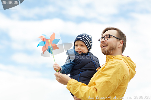 Image of happy father and son with pinwheel toy outdoors