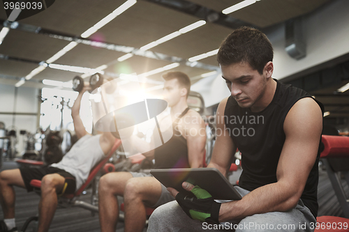 Image of group of men with tablet pc and dumbbells in gym