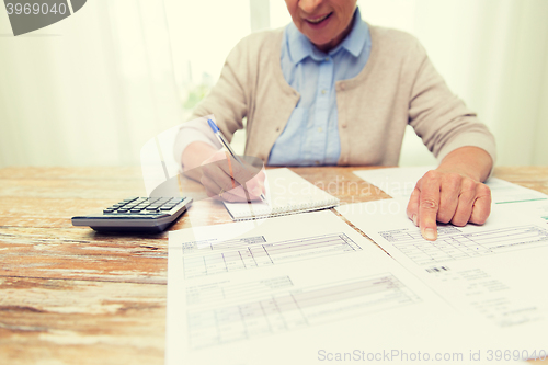 Image of senior woman with papers and calculator at home