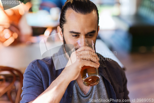 Image of happy man drinking beer at bar or pub