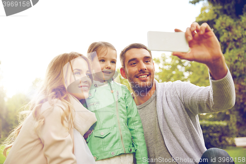 Image of happy family taking selfie by smartphone outdoors