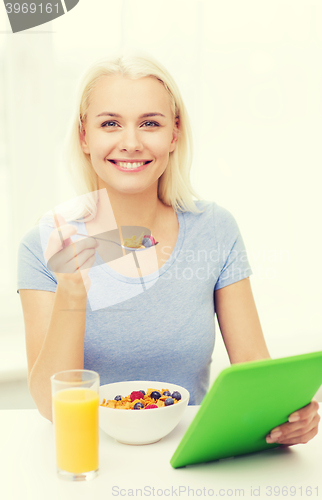 Image of smiling woman with tablet pc eating breakfast 