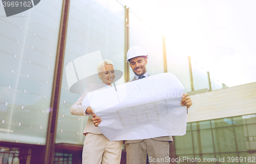 Image of smiling businessmen with blueprint and helmets