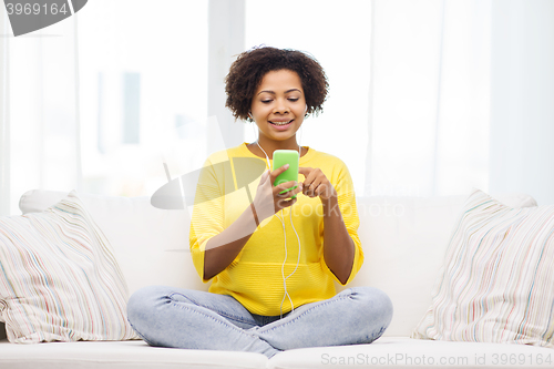 Image of happy african woman with smartphone and earphones