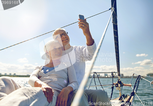 Image of senior couple taking selfie by smartphone on yacht