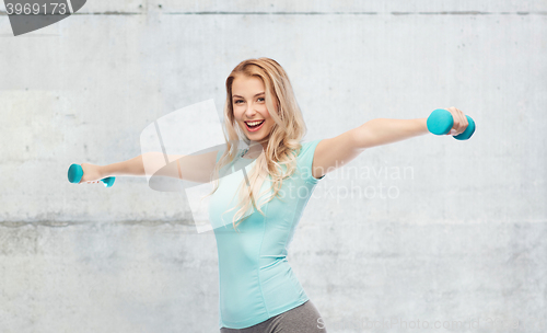 Image of smiling beautiful young sporty woman with dumbbell