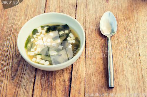 Image of bowl of soup with tofu cheese and spoon on table
