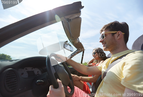 Image of happy couple driving in cabriolet car at country