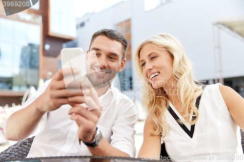 Image of happy couple with smatphone at restaurant terrace