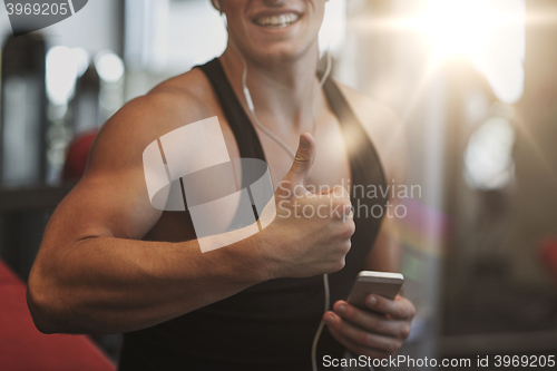 Image of happy man with smartphone and earphones in gym