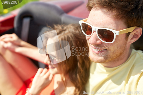 Image of happy couple driving in cabriolet car and hugging