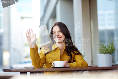 Image of happy woman drinking cocoa at city street cafe