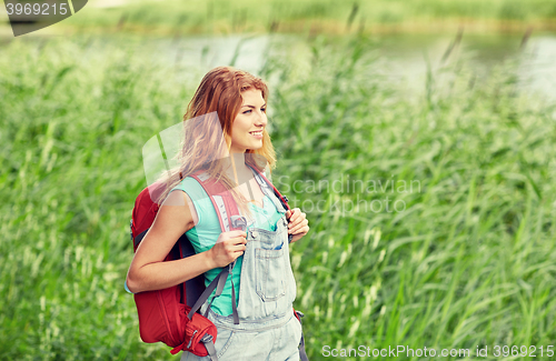 Image of smiling young woman with backpack hiking in woods