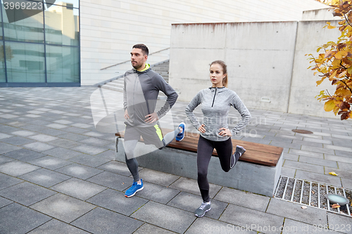 Image of couple doing lunge exercise on city street