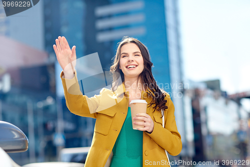 Image of happy young woman drinking coffee on city street