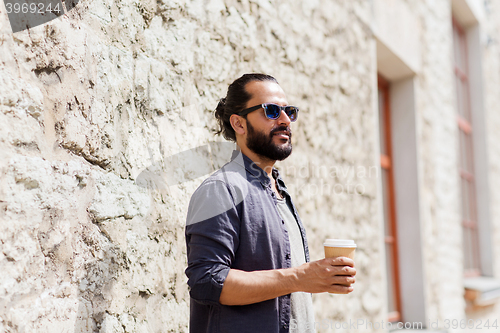 Image of man drinking coffee from paper cup on street