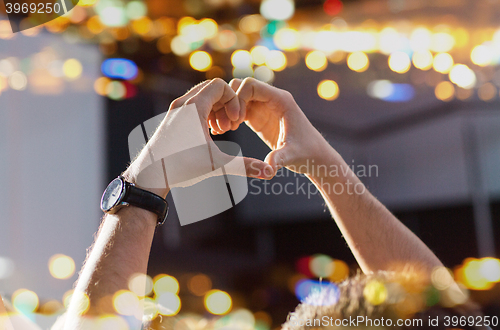 Image of close up of fan hands showing heart at concert