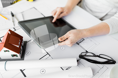 Image of close up of hand with blueprint and tablet pc