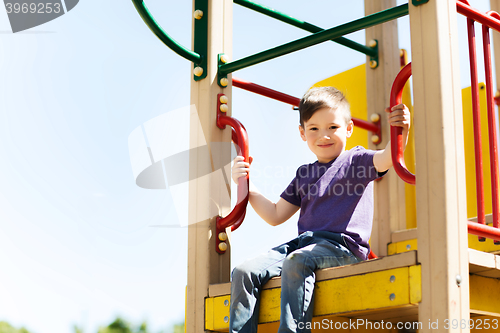 Image of happy little boy climbing on children playground