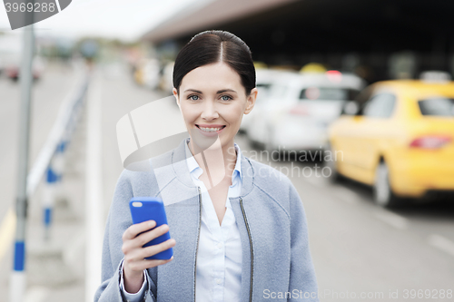 Image of smiling woman with smartphone over taxi in city