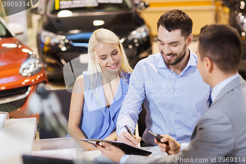 Image of happy couple with car dealer in auto show or salon