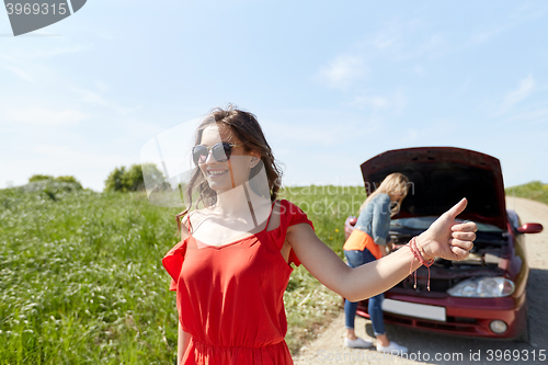 Image of women with broken car hitchhiking at countryside