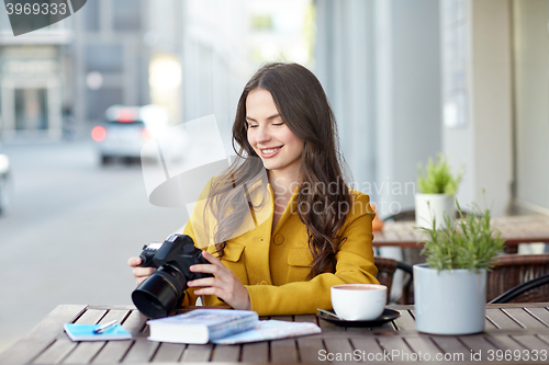 Image of happy tourist woman with camera at city cafe