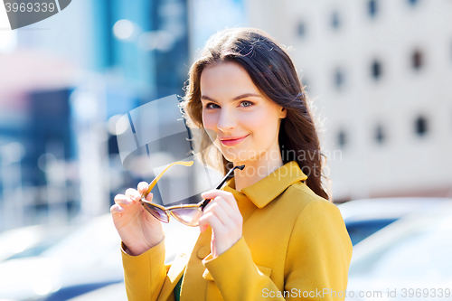 Image of smiling young woman with sunglasses in city