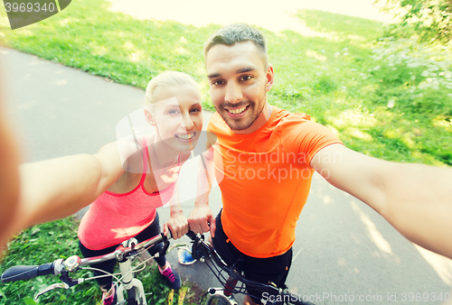 Image of couple with bicycle taking selfie outdoors