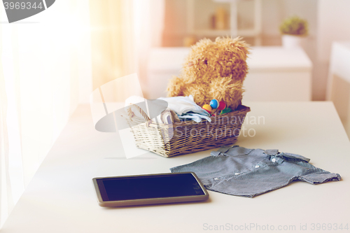 Image of close up of baby clothes, toys and tablet pc