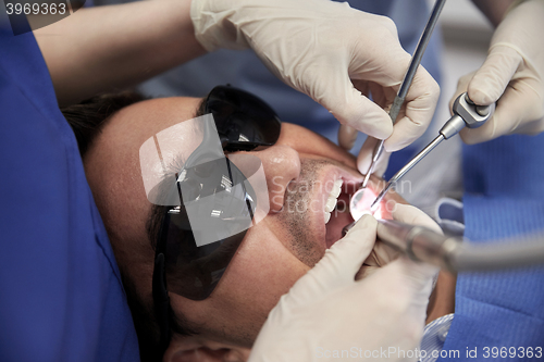 Image of dentist hands treating male patient teeth