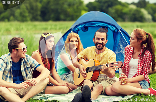 Image of happy friends with drinks and guitar at camping