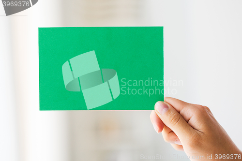 Image of close up of hand holding green paper card