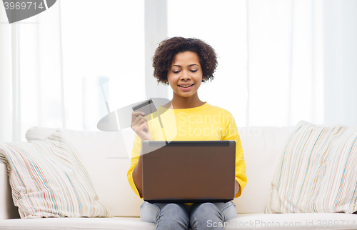 Image of happy african woman with laptop and credit card