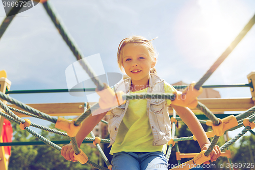 Image of happy little girl climbing on children playground