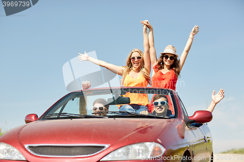 Image of happy friends driving in cabriolet car at country