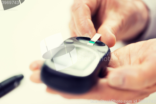 Image of senior woman with glucometer checking blood sugar