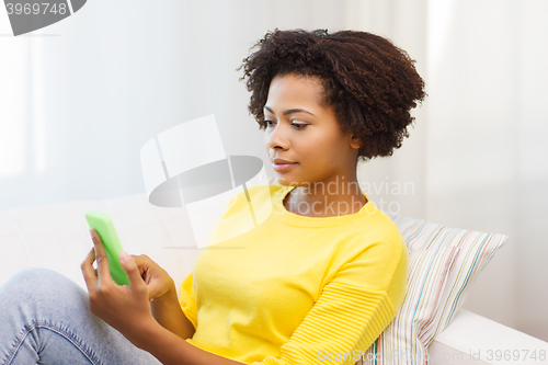 Image of happy african woman with smartphone at home