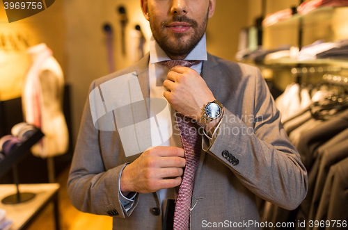 Image of close up of man tying tie at clothing store