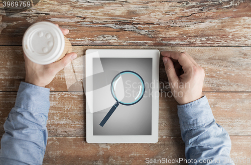 Image of close up of male hands with magnifier on tablet pc