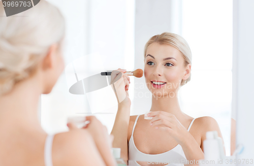 Image of woman with makeup brush and powder at bathroom