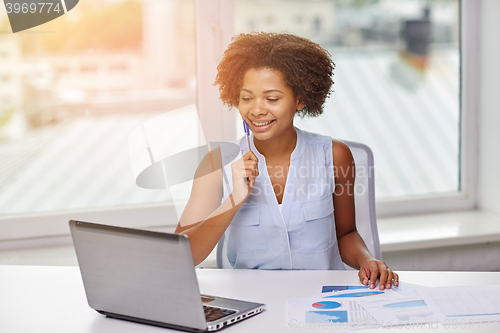 Image of happy african woman with laptop at office